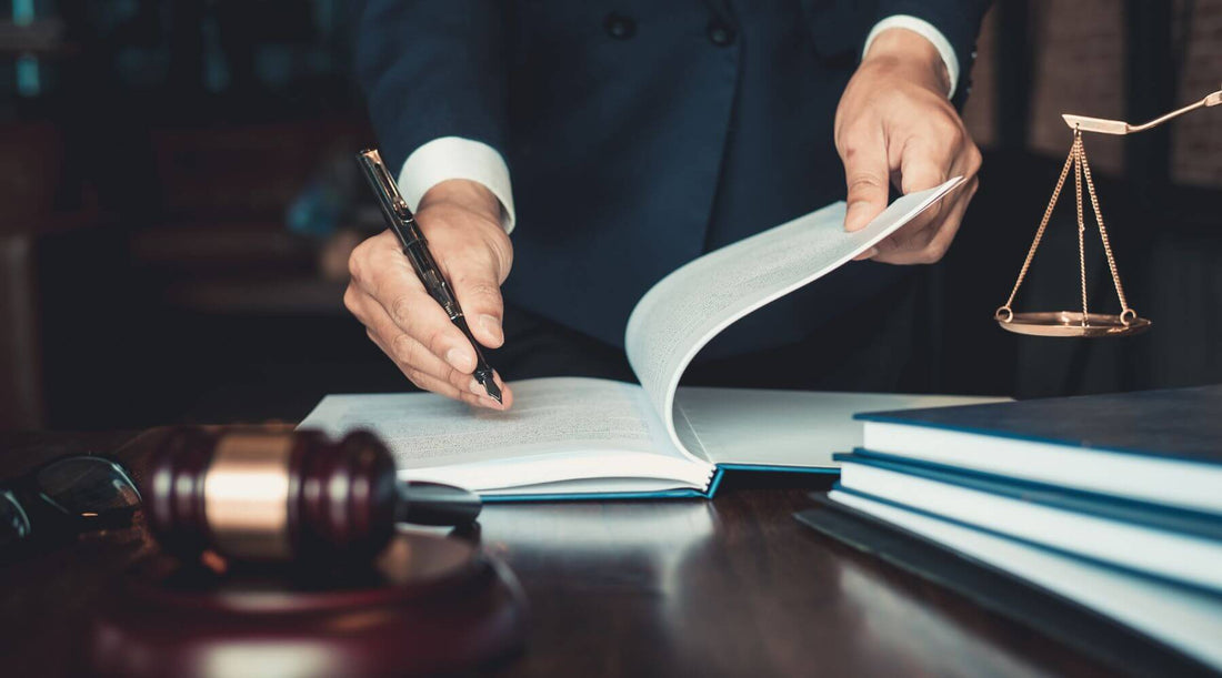 Photo d'une personne qui écrit dans un livre avec des instruments de justice autour de lui posés sur la table